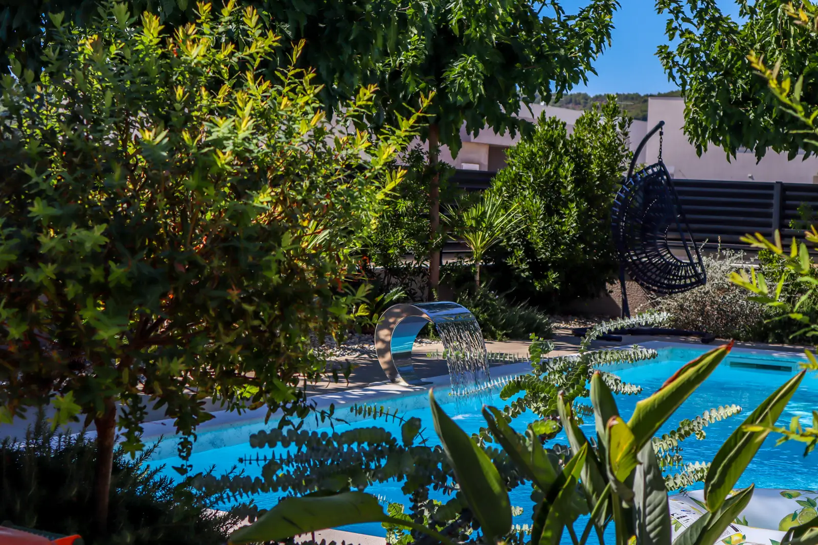 The pool framed by shrubs with the waterfall spout at its centre